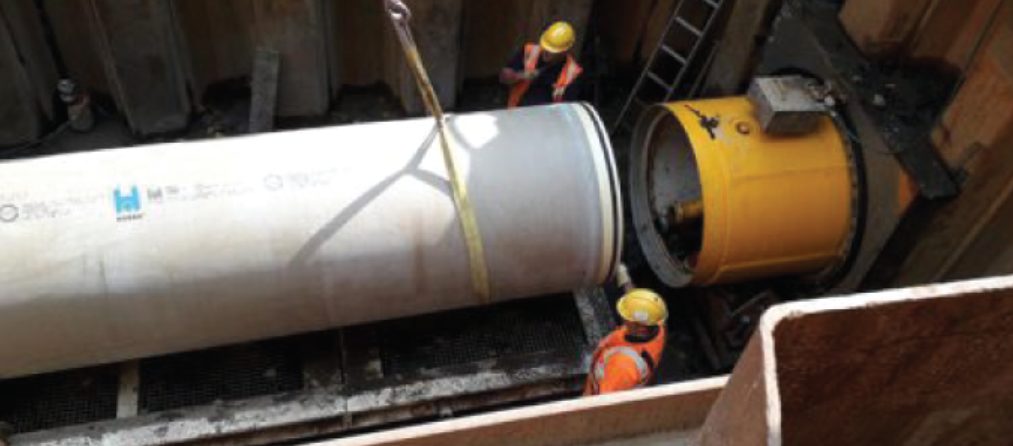 Crew lowering GRP pipe into shaft